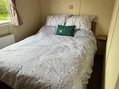 a bed with a white comforter and a green pillow at Sylvan in Builth Wells