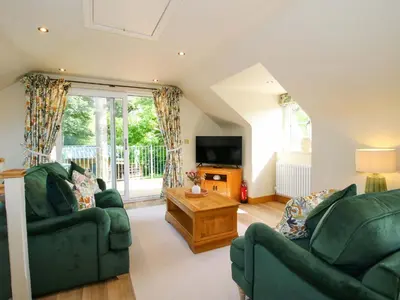 a living room with two green couches and a tv at The Hideaway in Shrewsbury