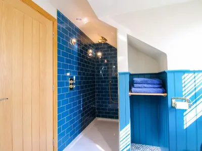 a blue bathroom with a shower with blue tiles at The Hideaway in Shrewsbury