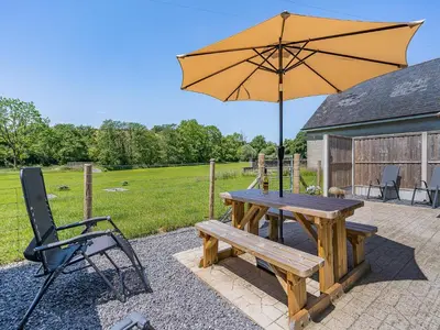 a wooden picnic table with an umbrella and a chair at The Old Cowsheds 5 - Llanilar - Uk49790 in Cribyn
