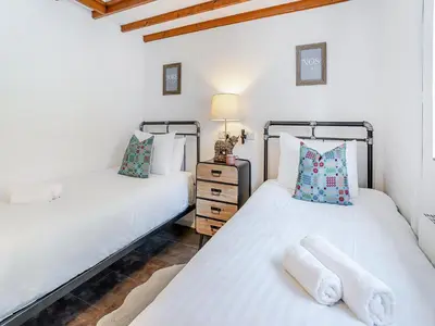 two twin beds in a room with white sheets at The Old Cowsheds 5 - Llanilar - Uk49790 in Cribyn