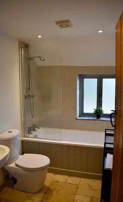 a bathroom with a toilet and a tub and a window at Zest Homes 87a Bridge Street in Leominster