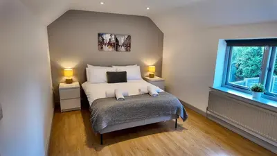 a bedroom with a bed with two night stands and two windows at Zest Homes 87a Bridge Street in Leominster