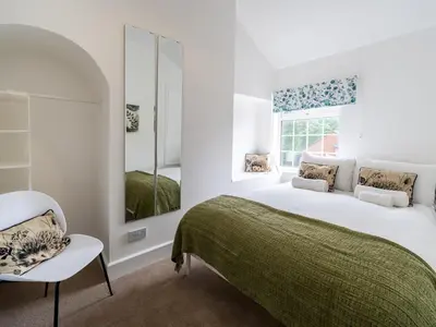 a white bedroom with a bed and a chair at Fantastic 3-bed home close to Shrewsbury centre - Pass the Keys in Shrewsbury