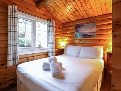 a bedroom with a bed in a log cabin at Y Bwthyn Pren, Cabin 209, in Trawsfynydd