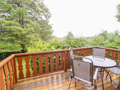 a porch with a table and chairs on a deck at Y Bwthyn Pren, Cabin 209, in Trawsfynydd