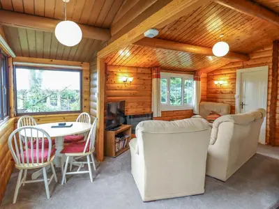 a living room with a table and chairs in a cabin at Y Bwthyn Pren, Cabin 209, in Trawsfynydd