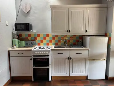 a kitchen with white cabinets and a stove and refrigerator at Nanternis Farm in New Quay