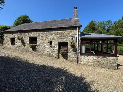 a stone building with a large window on the side at Nanternis Farm in New Quay