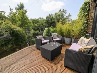 a patio with chairs and tables on a deck at The Old Barn in Lampeter