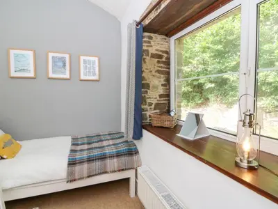a bedroom with a window and a bed and a table at The Old Barn in Lampeter