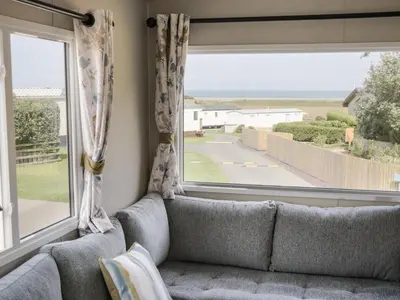 a living room with a couch and a large window at 8 Puffin Way in Llwyngwril