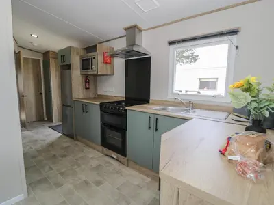 a kitchen with a sink and a stove at 8 Puffin Way in Llwyngwril