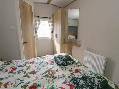 a bedroom with a bed with a floral bedspread at 8 Puffin Way in Llwyngwril