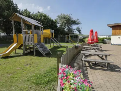 a park with a playground with benches and a slide at 8 Puffin Way in Llwyngwril