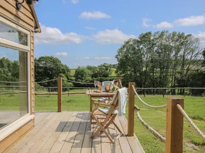 a wooden deck with a table and a view of a field at Owl's Hollow in Bucknell