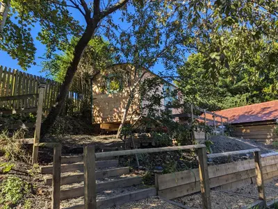 a wooden fence and stairs next to a tree at Myndy The Shepherd's Hut in Church Stretton