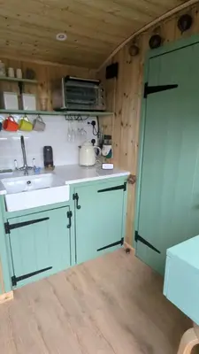 a kitchen with blue cabinets and a sink and a door at Myndy The Shepherd's Hut in Church Stretton