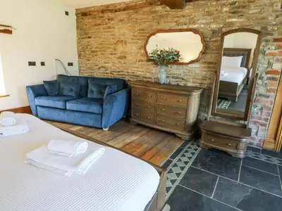 a living room with a blue couch and a mirror at Stud Farm House in Knighton