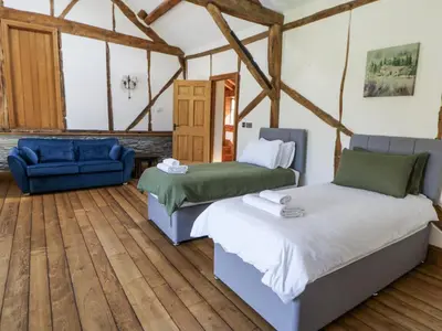 a bedroom with two beds and a blue couch at Stud Farm House in Knighton