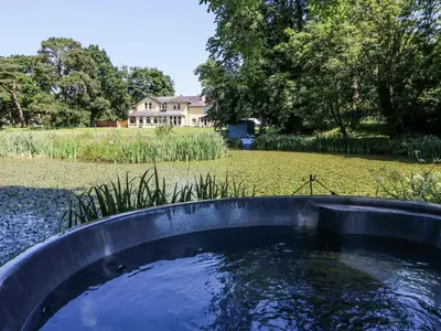 a pool of water with a house in the background at The Retreat at Glanrannell Park House in Llanwrda