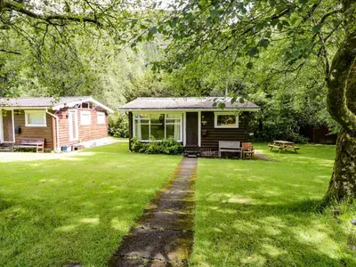 a log cabin with a table and a bench in a yard at Ty Bedwen in Machynlleth
