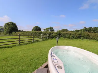 a bath tub in a field next to a fence at Bwthyn Bach Brefi in Tregaron
