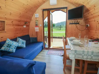 a living room with a blue couch and a table at Ty Twt Teifi in Tregaron