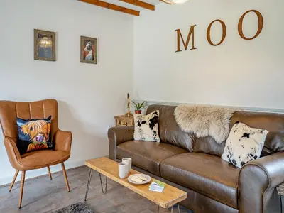 a living room with a brown couch and a chair at The Old Cowsheds 3 - Mynach - Uk49788 in Cribyn