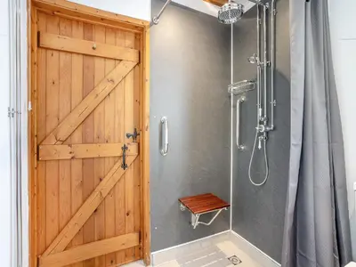 a bathroom with a shower with a wooden door at The Old Cowsheds 2 - Shippon - Uk49787 in Cribyn