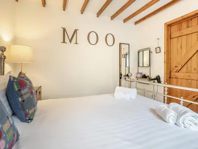 a bedroom with a large white bed with a wooden headboard at The Old Cowsheds 2 - Shippon - Uk49787 in Cribyn