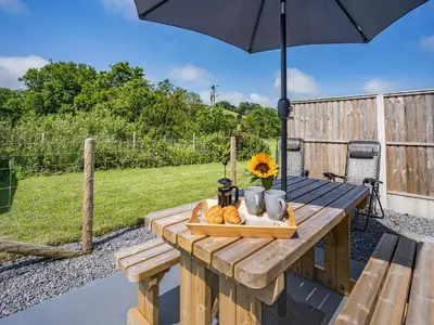 a wooden table with an umbrella and a bowl of bread at The Old Cowsheds 1- Dairy - Uk49786 in Cribyn