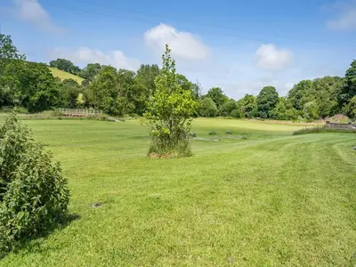 a field with a tree in the middle of it at The Old Cowsheds 1- Dairy - Uk49786 in Cribyn