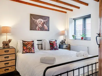 a bedroom with a white bed with a cow painting on the wall at The Old Cowsheds 1- Dairy - Uk49786 in Cribyn