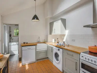 a kitchen with white cabinets and a washer and dryer at Clee View Cottage in Ludlow