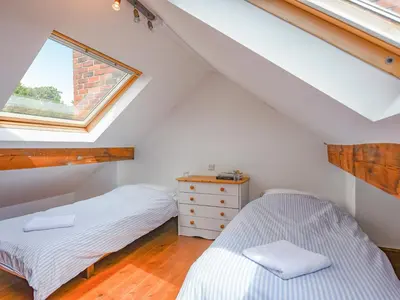 two beds in a attic bedroom with a window at Clee View Cottage in Ludlow