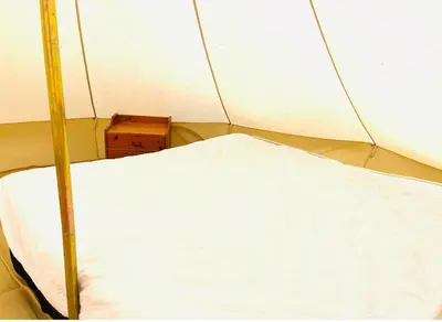a white bed in a tent with a wooden box at Bell Tent - Lakeside in Oswestry