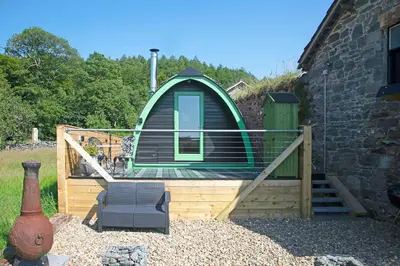 a green cabin with a deck and a chair at Scenic Pet Friendly Pod in Talybont Aberystwyth in Aberystwyth