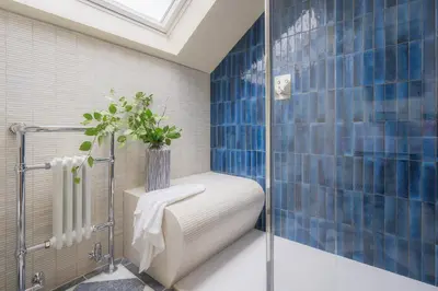 a blue tiled bathroom with a shower with a toilet at Llys y wawr Luxury Holiday Let in Aberystwyth