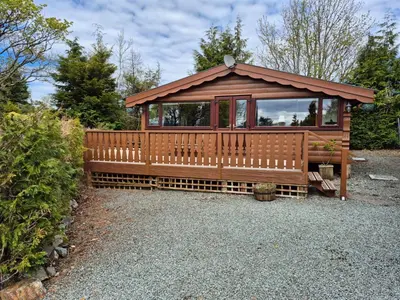 a wooden cabin with a large window on top at Caban Enfys in Trawsfynydd