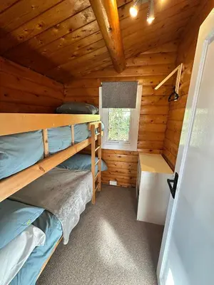 a bedroom with two bunk beds in a log cabin at Caban Enfys in Trawsfynydd