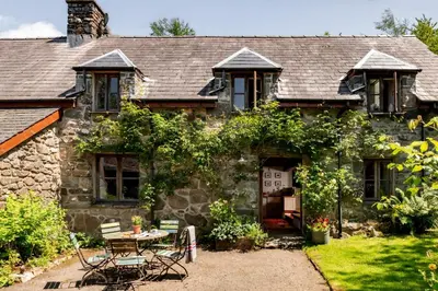 an old stone house with a table and chairs at Ty Neuadd in Dolgellau