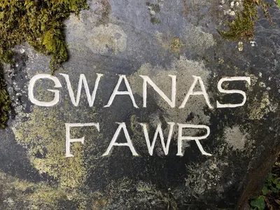 a sign on a rock that reads unnamed farm at Ty Neuadd in Dolgellau