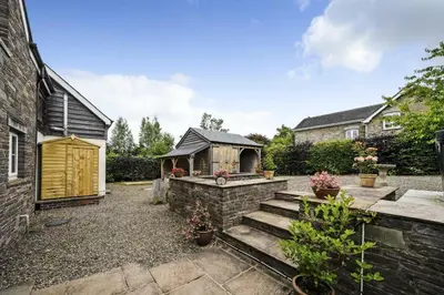 a backyard with a stone wall and a wooden structure at Priory cottage in Clifford