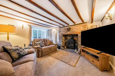a living room with a flat screen tv and a fireplace at Priory cottage in Clifford