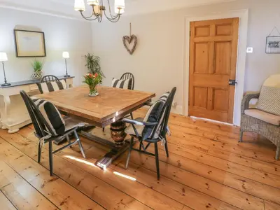 a dining room with a wooden table and chairs at Bwthyn Mawr in Harlech