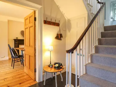 a hallway with stairs and a table and a lamp at Bwthyn Mawr in Harlech