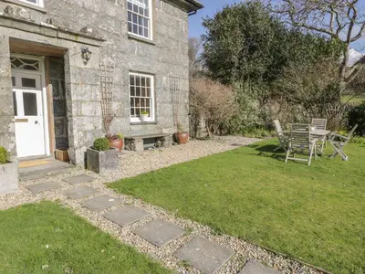 a garden with a table and chairs in front of a house at Bwthyn Mawr in Harlech