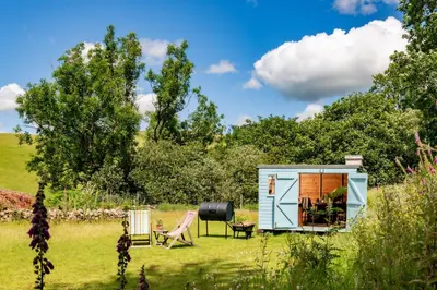 a tiny caravan in a field with a table and chairs at Ty Trol in Dolgellau