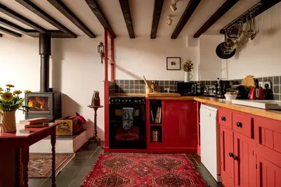 a kitchen with red cabinets and a stove at Ty Trol in Dolgellau